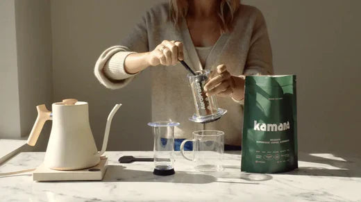 Caffeine-free drinks like Kamana mesquite coffee alternative being prepared with an AeroPress on a marble countertop in natural lighting