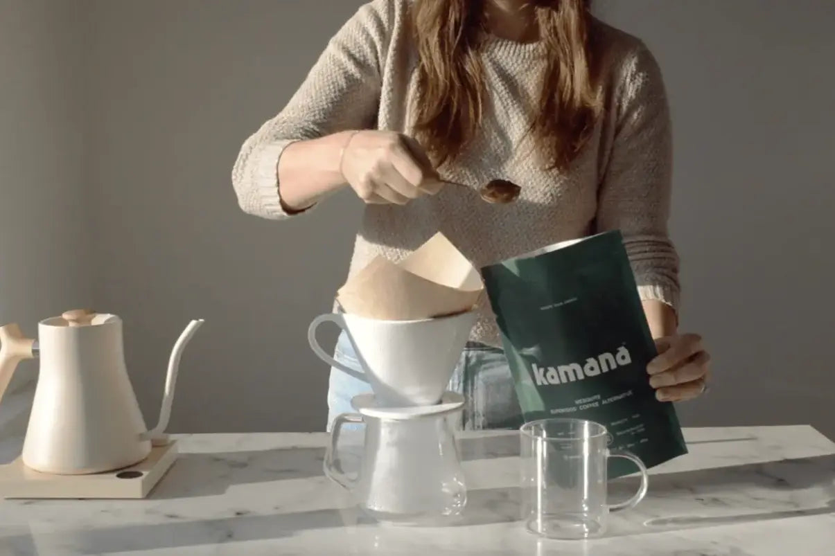 Natural caffeine alternatives being prepared using a pour-over method, with a woman scooping Kamana mesquite coffee into a filter.